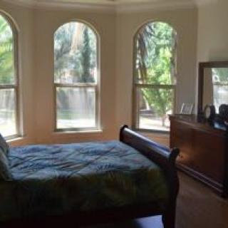 A cozy bedroom with large arched windows allowing abundant natural light in.