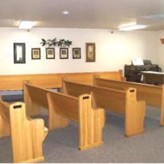 Interior view of a small church with wooden pews and decorations.