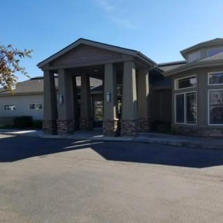A commercial building with a prominent entrance and stone accents under a clear blue sky.