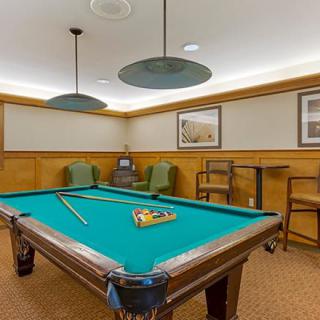 A billiard room with a pool table, cue sticks, and seating area.