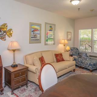 A cozy living room featuring a sofa, armchair, and decorative artwork on the walls.