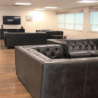 A modern office lounge with leather sofas and a television.