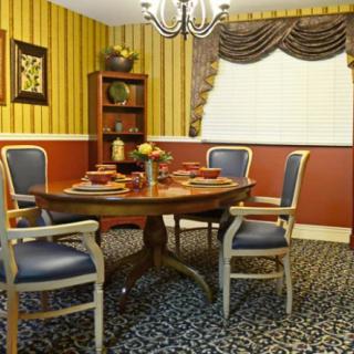 A traditional dining room with a round table, upholstered chairs, decorative curtains, and striped wallpaper.