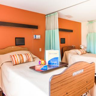 A cozy hotel room featuring two beds with a warm orange accent wall, designed for comfort and relaxation.