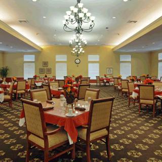 A spacious dining room with neatly arranged tables and elegant chandeliers.
