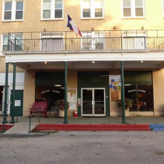 A charming storefront with a welcoming entrance and a flag displayed overhead.