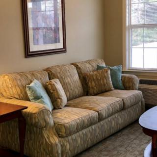 A cozy living room with a patterned sofa, decorative pillows, and a wooden table by the window.