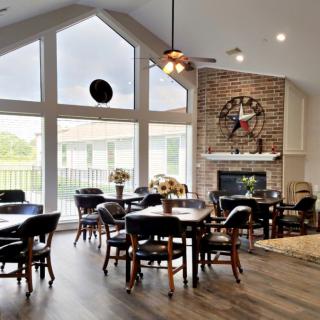 A spacious dining area with large windows, a fireplace, and vaulted ceilings, featuring elegant wooden furniture.