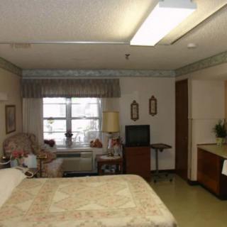 A hospital room with a bed, television, and window with curtains.