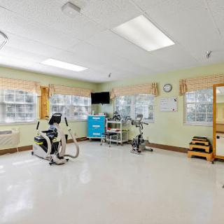 A well-lit rehabilitation room featuring various exercise machines and a clean, spacious layout.