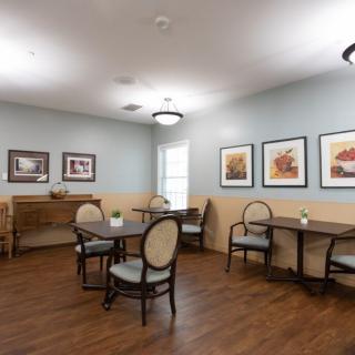 A cozy dining area with tables and chairs, adorned with artwork on the walls.