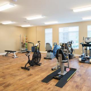 A well-equipped gym with various exercise machines and equipment in a spacious, brightly lit room.