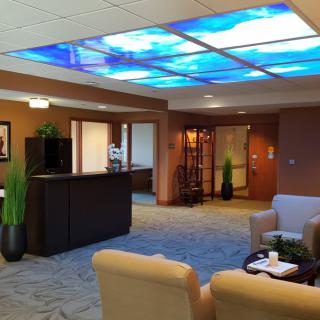 A modern reception area with comfortable seating and illuminated ceiling panels.