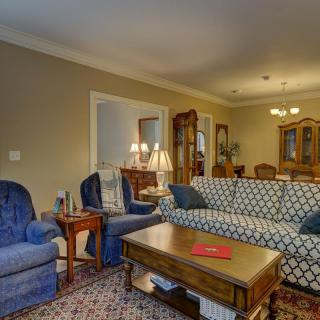 A cozy living room with traditional decor, featuring a patterned sofa, blue armchairs, and a wooden coffee table.