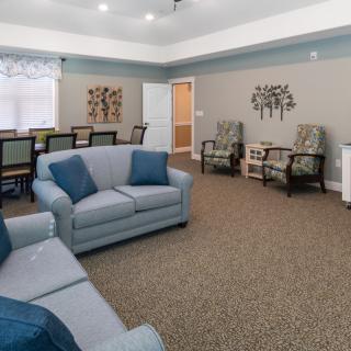 A cozy living room with sofas, chairs, and a dining table.