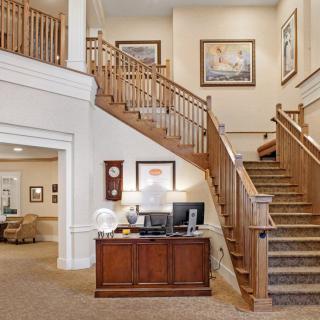 A warmly decorated interior featuring a wooden staircase, artwork on the walls, and a reception desk.