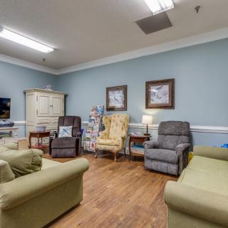 A cozy living room with various chairs and sofas arranged around a wooden floor.