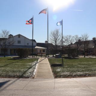 A view of a building with flags flying in the foreground on a sunny day.