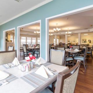 A spacious dining room with neatly arranged tables and chairs, featuring elegant place settings.