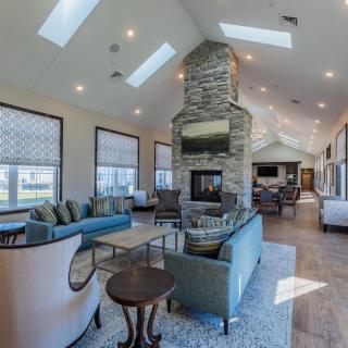 A spacious modern living room with a central stone fireplace and skylights.