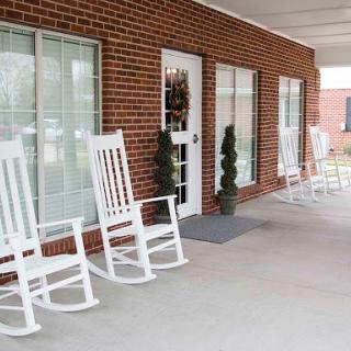 A cozy porch featuring white rocking chairs, inviting guests to relax.