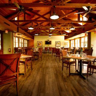 A cozy restaurant with a warm wooden interior and neatly arranged tables and chairs.