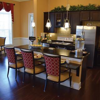 A modern kitchen and dining area with pendant lights, a countertop, and stylish seating.