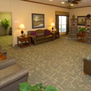 A spacious living room with comfortable seating, decorative lamps, and framed artwork on the walls.