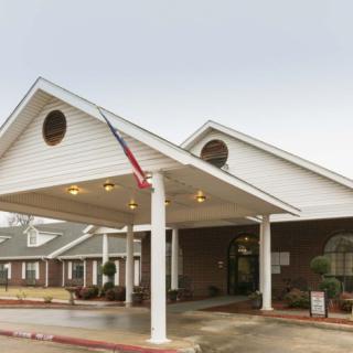 A building with a large entrance and an awning, featuring a flag.