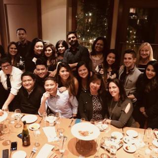 A large group of people gathered around a dinner table, celebrating together in a restaurant setting.