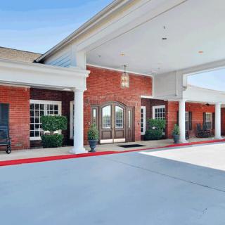 Entrance of a red brick building with a covered walkway and white columns.