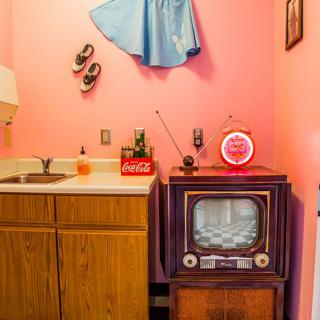 A vintage kitchen setup featuring a retro television against pink walls, capturing the essence of a 1950s style.