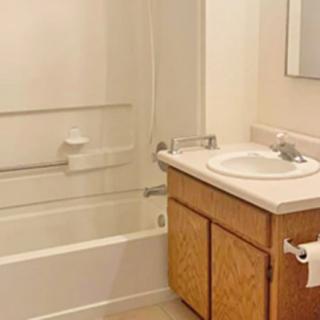 A simple bathroom featuring a sink, bathtub, and cabinet.