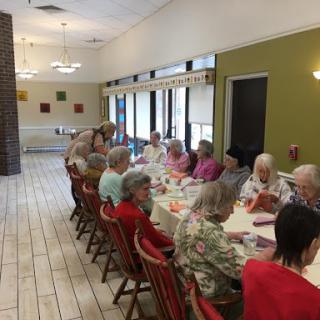 A gathering of seniors enjoying a meal together in a community dining area.