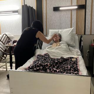 A caregiver attending to a patient in a hospital room.