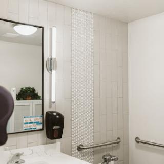 A modern bathroom featuring a sleek sink, mirror, and efficient lighting.
