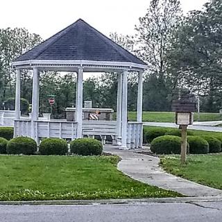 A serene view of a gazebo surrounded by lush greenery in a park.