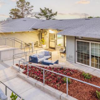 A beautifully designed modern house with inviting outdoor seating, showcasing elegant landscaping under soft evening light.