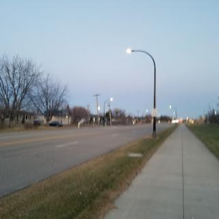 A tranquil evening scene showcasing a quiet street with lampposts and trees.