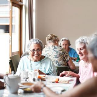 A group of elderly individuals enjoying a meal together in a communal dining setting.