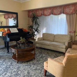A cozy living room featuring a grand piano, comfortable seating, and elegant decor.