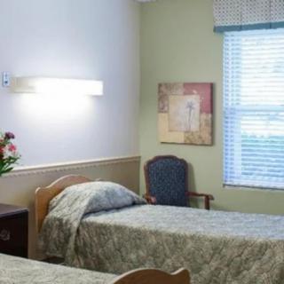 A hospital room with two beds, a window, and wall decorations.