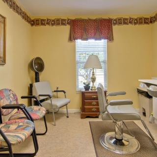 A cozy waiting room with chairs, a fan, and a table by the window.