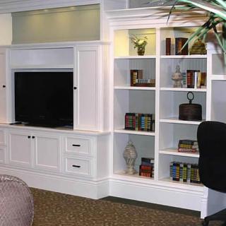 A modern living room with built-in white shelving and a TV unit.