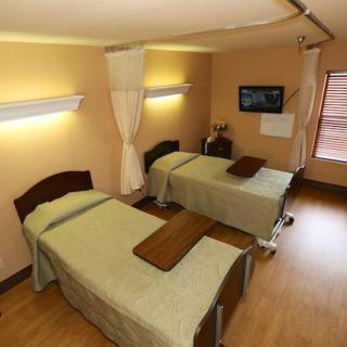 A hospital room with twin beds, curtains, and medical equipment.