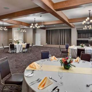 An elegantly decorated banquet hall set up with round dining tables and chandeliers.
