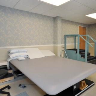 A physical therapy room equipped with a padded exercise table and rehabilitation stairs.