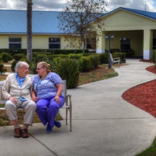 Elderly couple sitting on a bench in the garden of a nursing home.