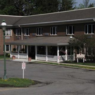 A two-story residential building with a covered entrance and surrounding greenery.