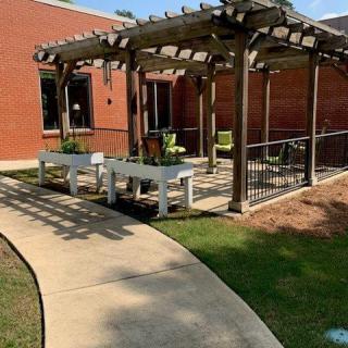 An outdoor patio area with a pergola, seating, and landscaped walkway.